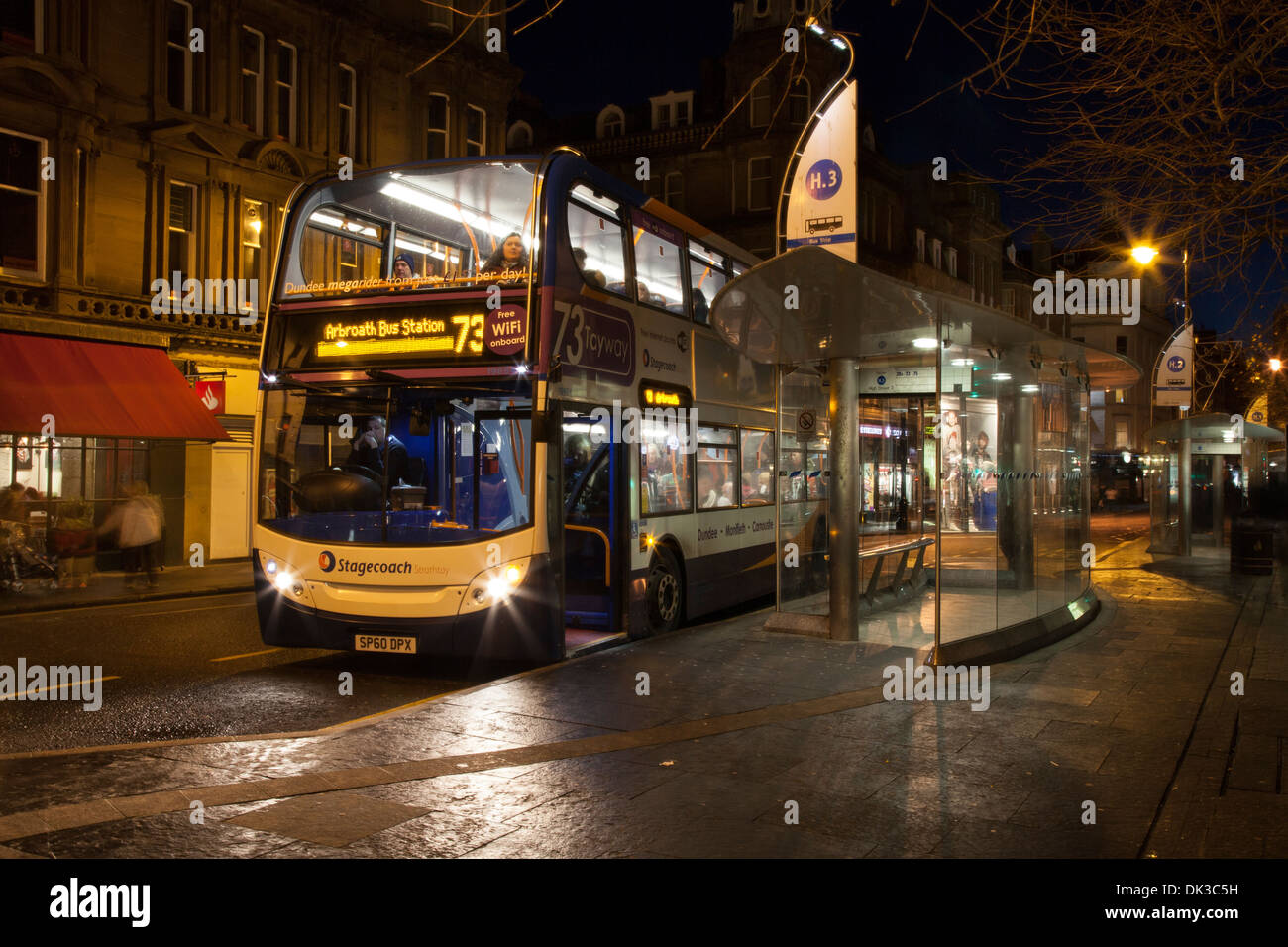 Regnerische Nacht Szene, Straßenbeleuchtung & öffentliche Verkehrsmittel in die Stadt Dundee. National Express Busbahnhof im Regen in der Dämmerung, Schottland, Großbritannien Stockfoto