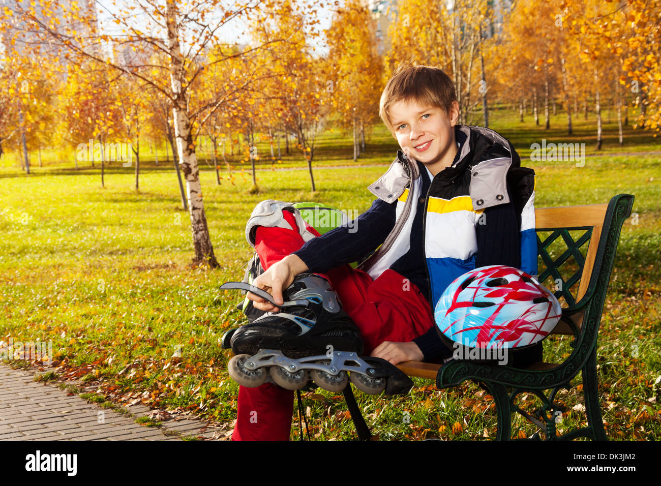 10 Jahre alter Junge sitzt auf der Bank im Herbst immer bereit, außerhalb skate park Stockfoto