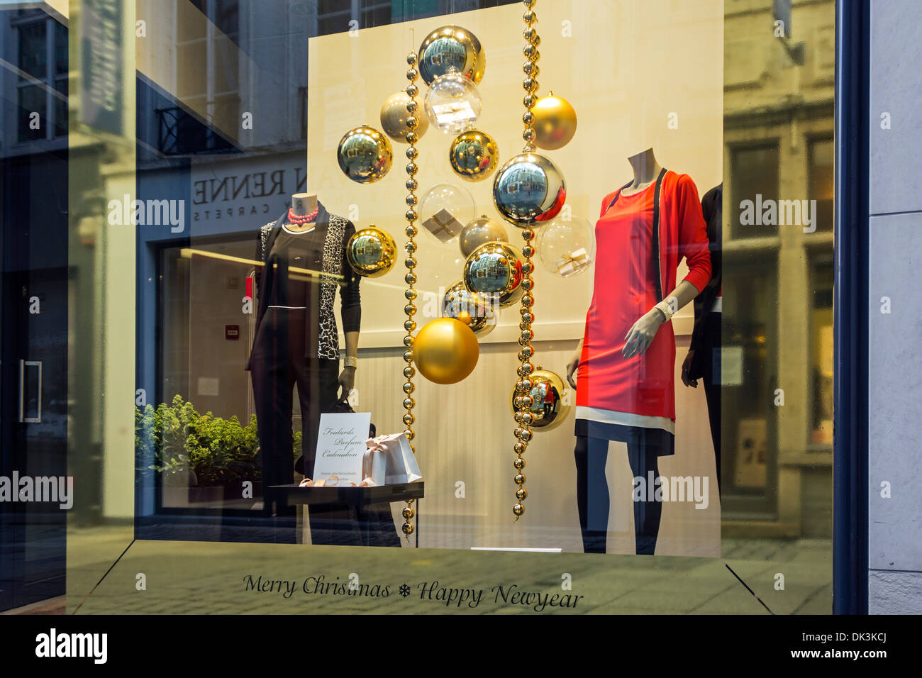 Weihnachtsschmuck im Schaufenster der Kleidung aufbewahren zeigen festliche Kleider in Einkaufsstraße im winter Stockfoto