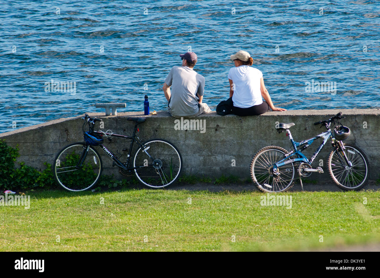 Zwei junge Männer ruhen am See nach dem Radfahren, Seattle, Bundesstaat Washington, USA Stockfoto