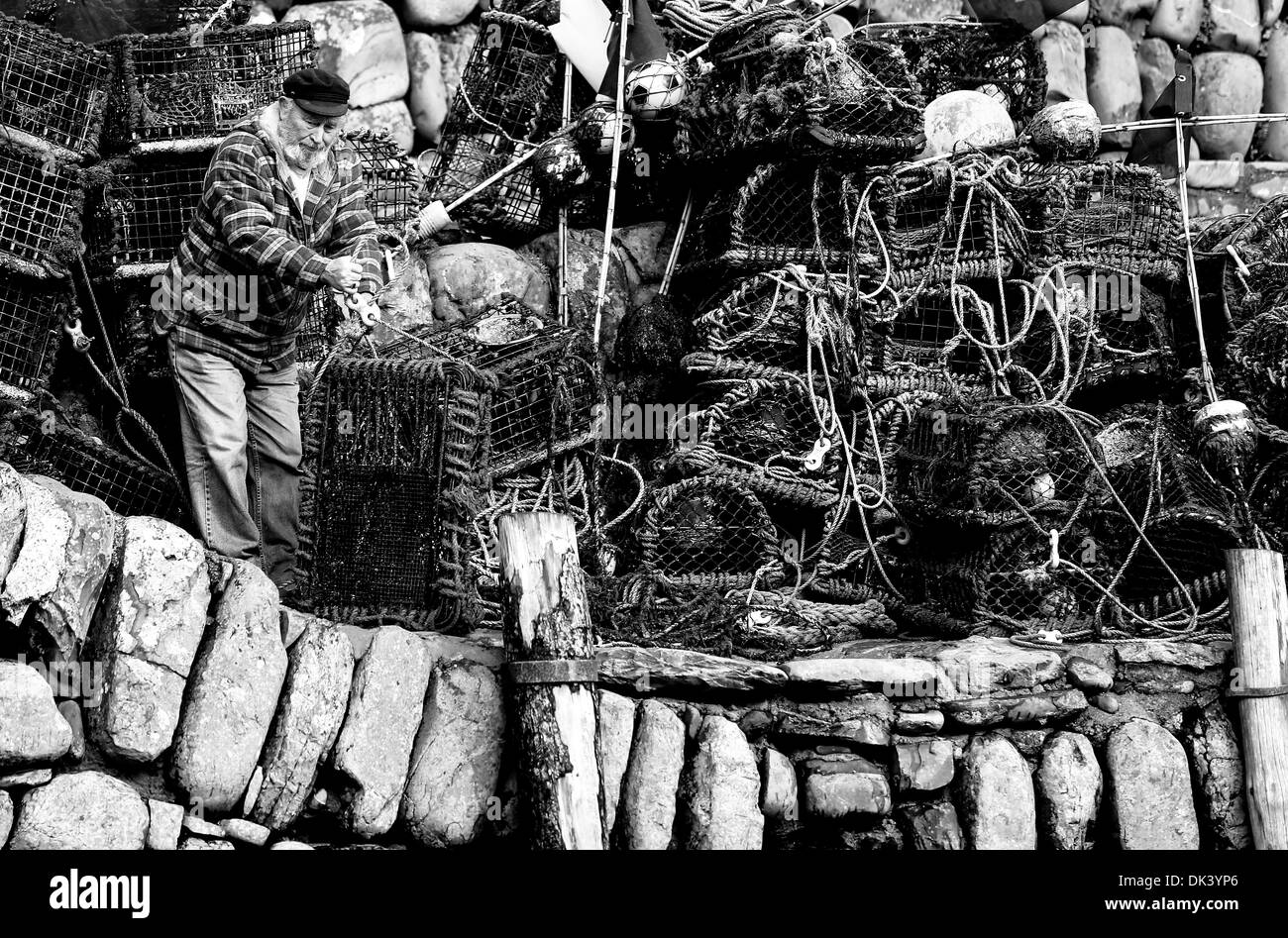 Ein Fischer prüft seine Hummer-Töpfe nach dem Sturm auf die Kaimauer in Clovelly, North Devon. Stockfoto