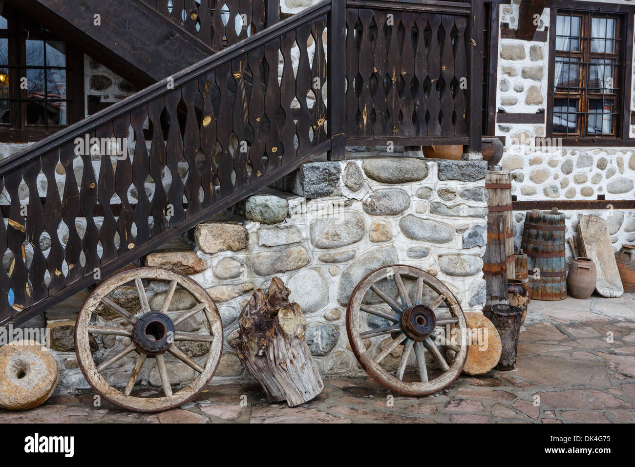Räder aus einer Karre, alten Holzfässern und Steinen als Dekoration eine Außenansicht des Hauses Stockfoto