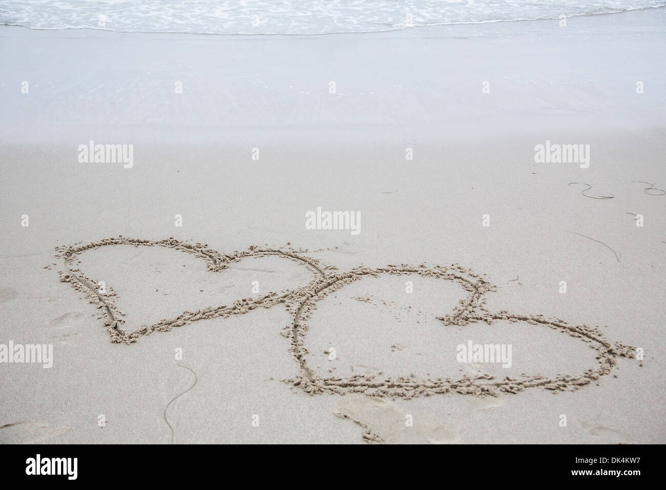 Zwei Herzen in nassem Sand gehauen Stockfoto