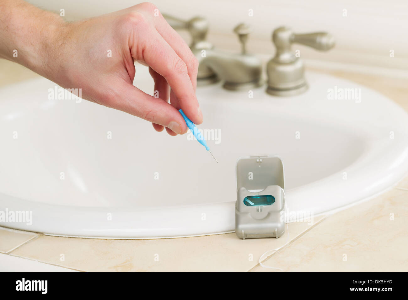 Horizontale Foto der männlichen Hand dental Zahn Abholung wählen Sie im Bad mit Zahnseide Container, Spüle und Theke top Stockfoto