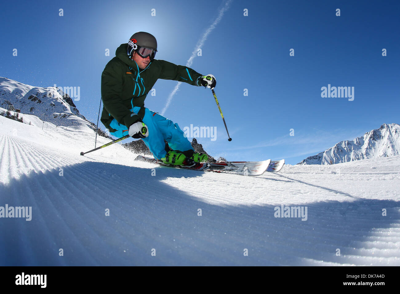 Breite Nahaufnahme eines Skifahrers Fahren einer scharfen Kurve im Schnee an einem sonnigen Tag mit blauen Himmel Stockfoto