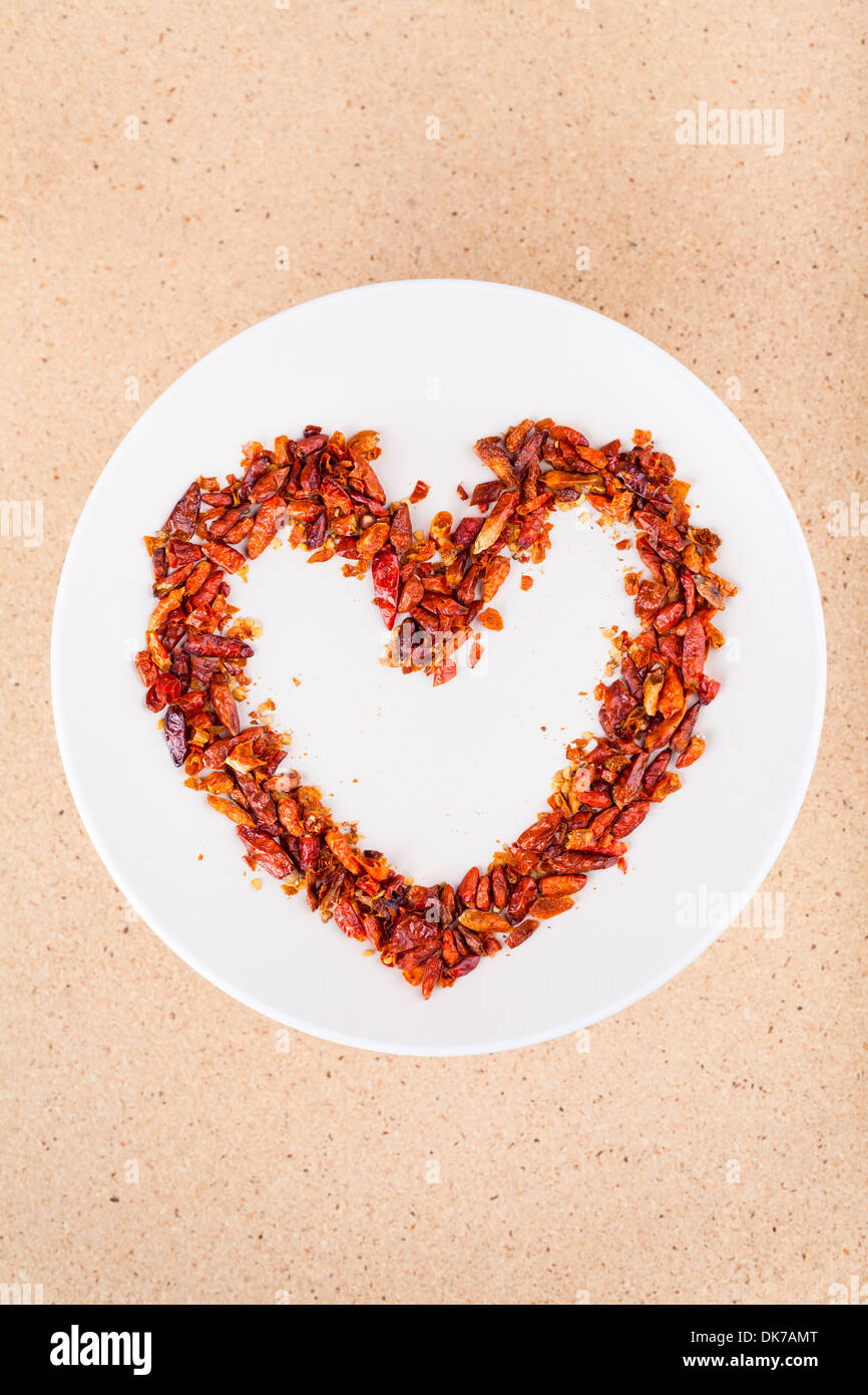 Heiße Liebe Konzept, rote Chilischoten auf Teller in Herzform angeordnet. Stockfoto