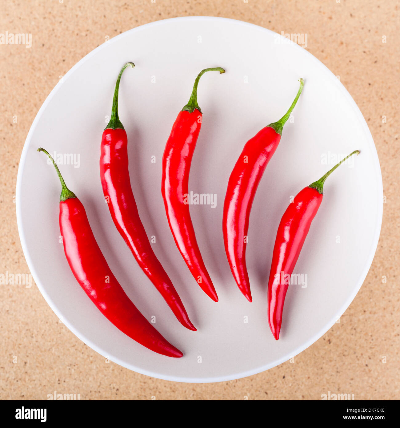 Frische rohe rote scharfe Chilischoten auf Teller, in hellem Holz Hintergrund. Stockfoto