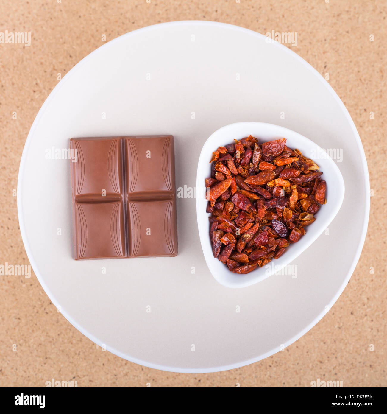 Getrocknete rote scharfe Chilischoten mit Schokolade auf Teller, in hellem Holz Hintergrund. Stockfoto