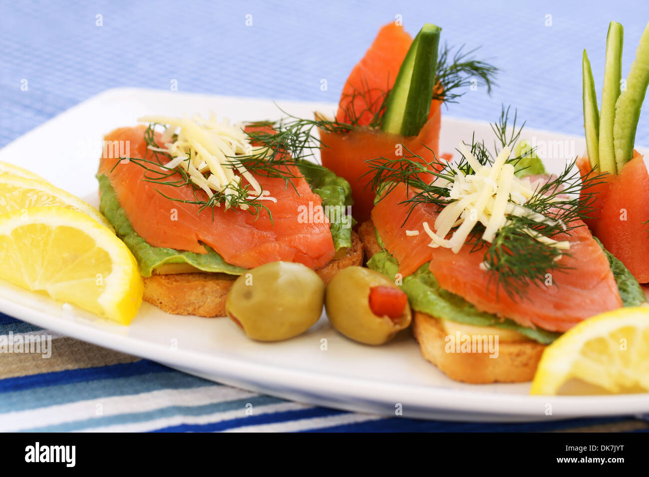 Sandwiches mit Lachs, Käse, Salat, Kräuter auf Teller, Oliven und Zitronen. Stockfoto