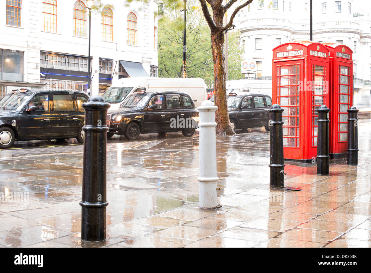 Rote Telefon Kabinen in London und Vintage Taxi. Regnerischen Tag. Vintage Telefon Cabine monumentale Stockfoto