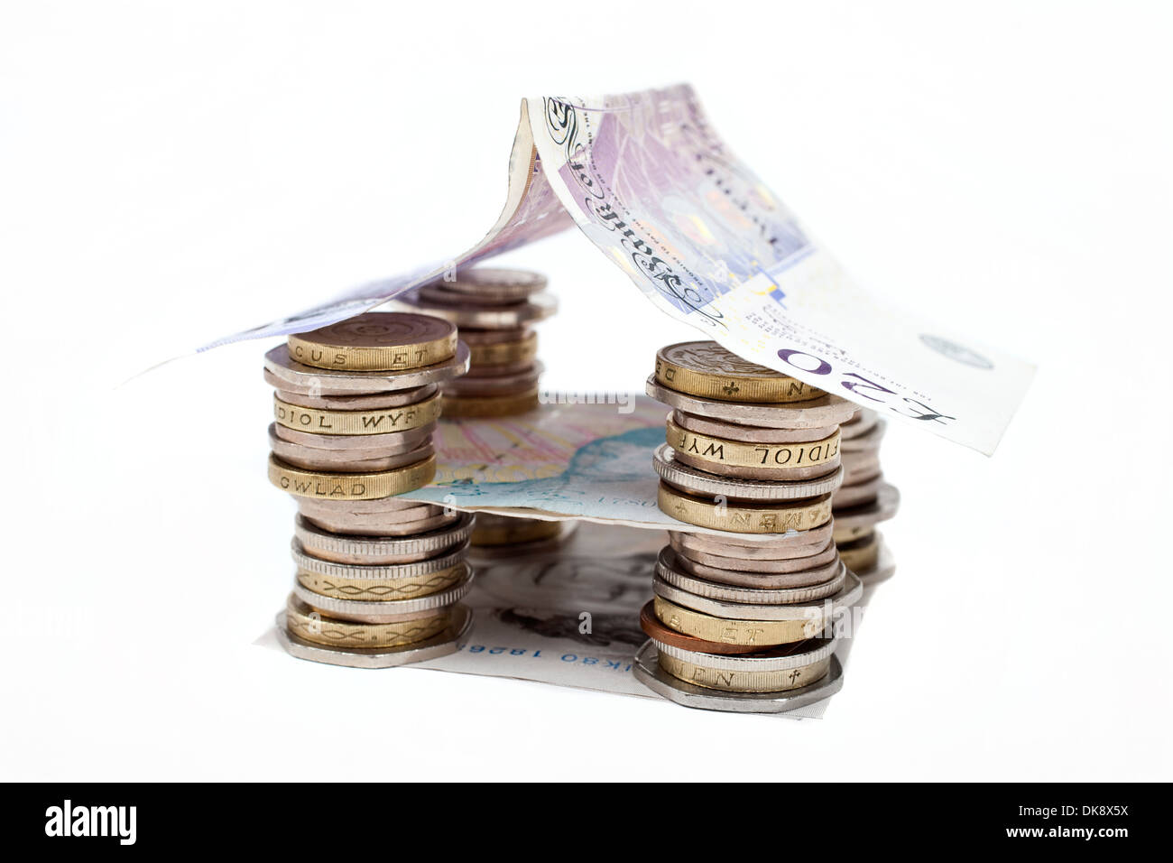 Münzen und Banknoten, die in ein Haus gebaut. Stockfoto