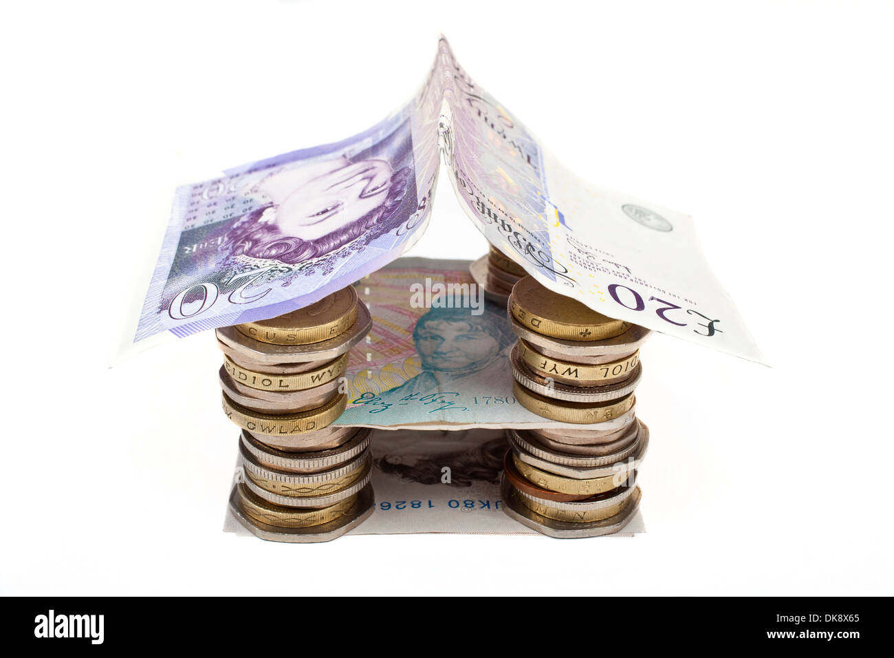 Münzen und Banknoten, die in ein Haus gebaut. Stockfoto