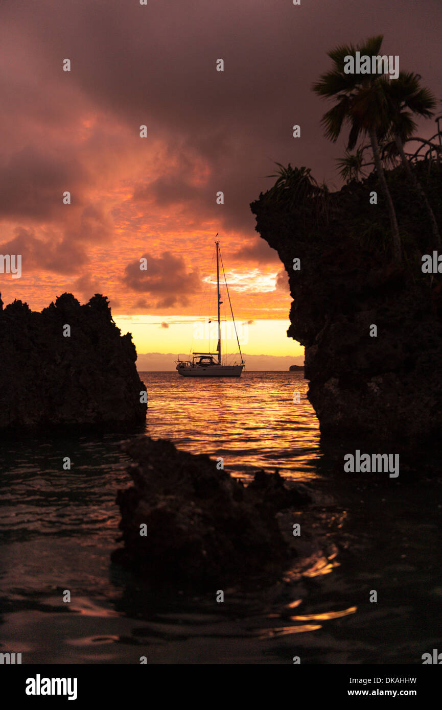 Roter Himmel im Morgengrauen, eine Yacht in der Nähe von Kalkstein Motus (Inseln) in Fulaga Lagune, südlichen Lau Inseln Fidschi verankert. Stockfoto