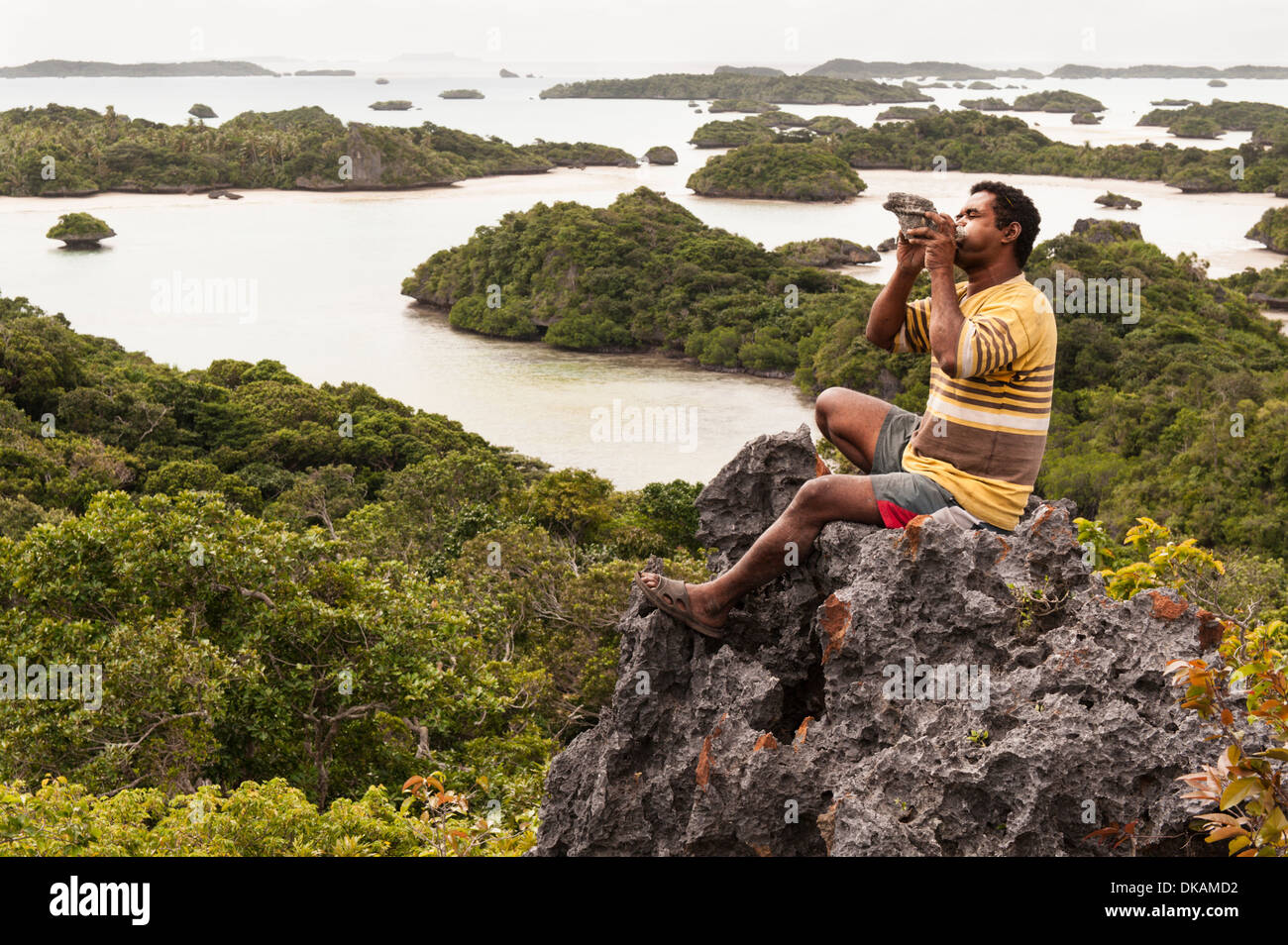 Meli Yasabalavu bläst eine Warnung Shell vom Aussichtspunkt auf der Insel Narocake in der Fulaga Lagune, südlichen Laus Fidschi Stockfoto