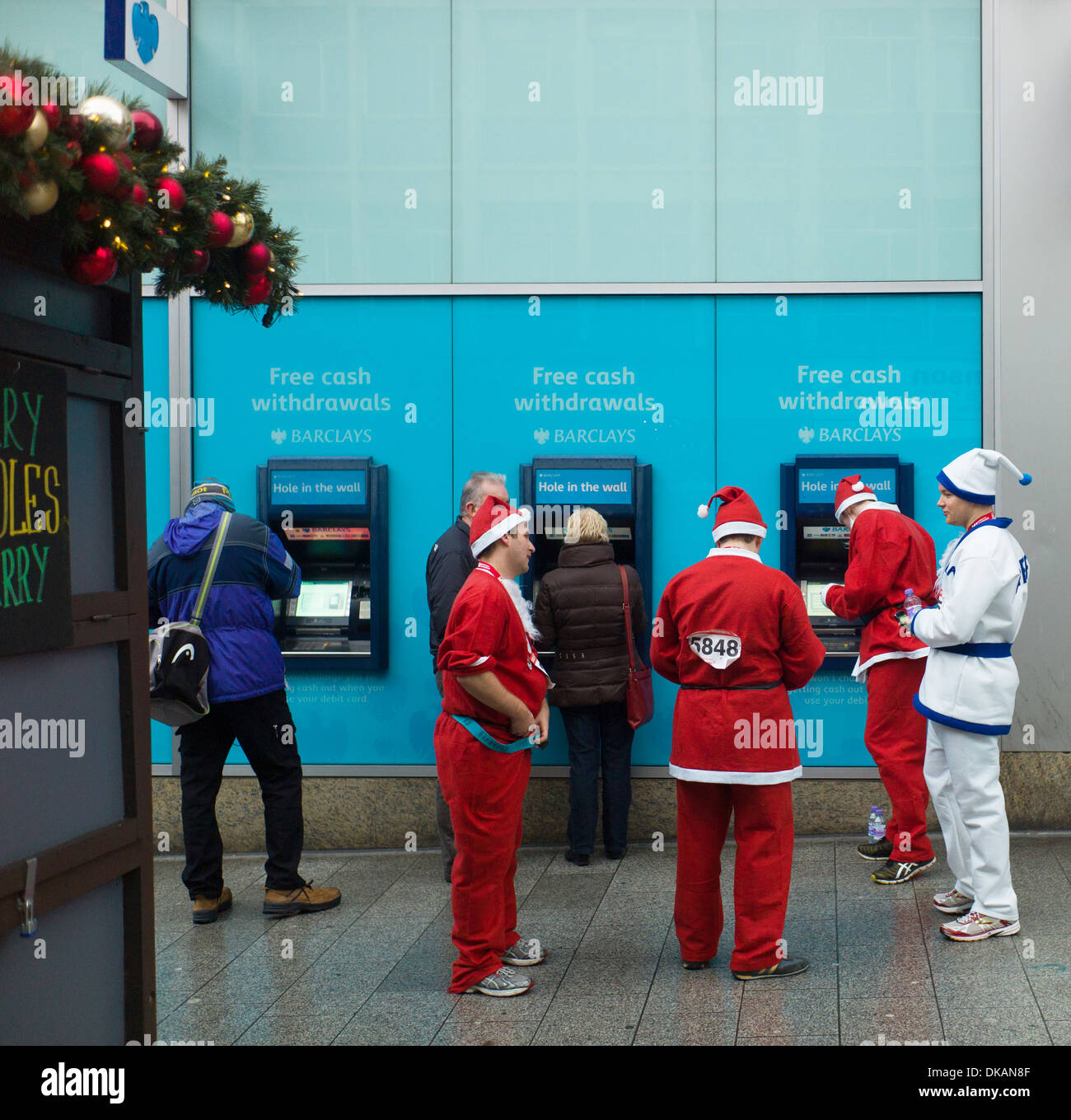 Nächstenliebe Santa Dash in Liverpool Läufer Pause um Geld bei Barclays Loch in der Wand-Geldautomat Stockfoto