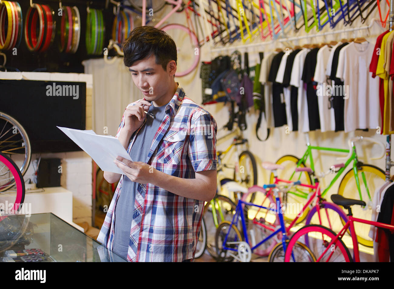 Junger Mann im Bike-Shop hält Papierkram Stockfoto
