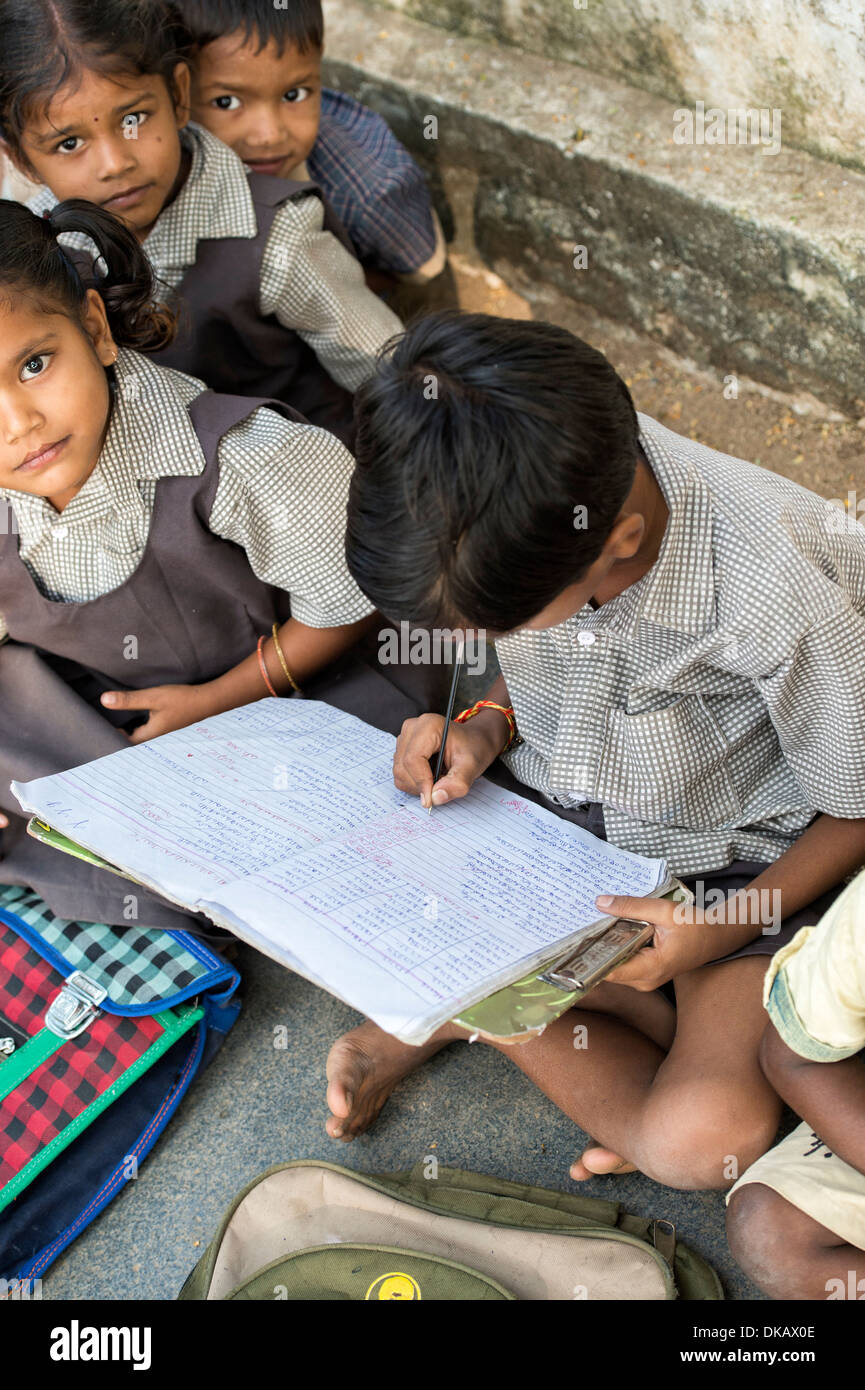 Indische Bauerndorf Schuljunge in einem Lehrbuch in einer externen Klasse schreiben. Andhra Pradesh, Indien Stockfoto
