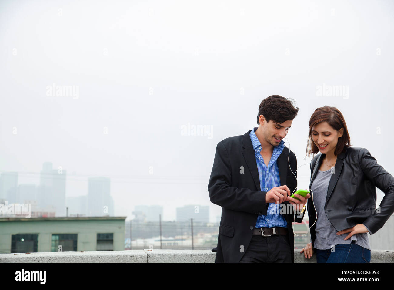 Paar anhören freigegebenen Ohrstöpsel auf Stadt auf dem Dach Stockfoto