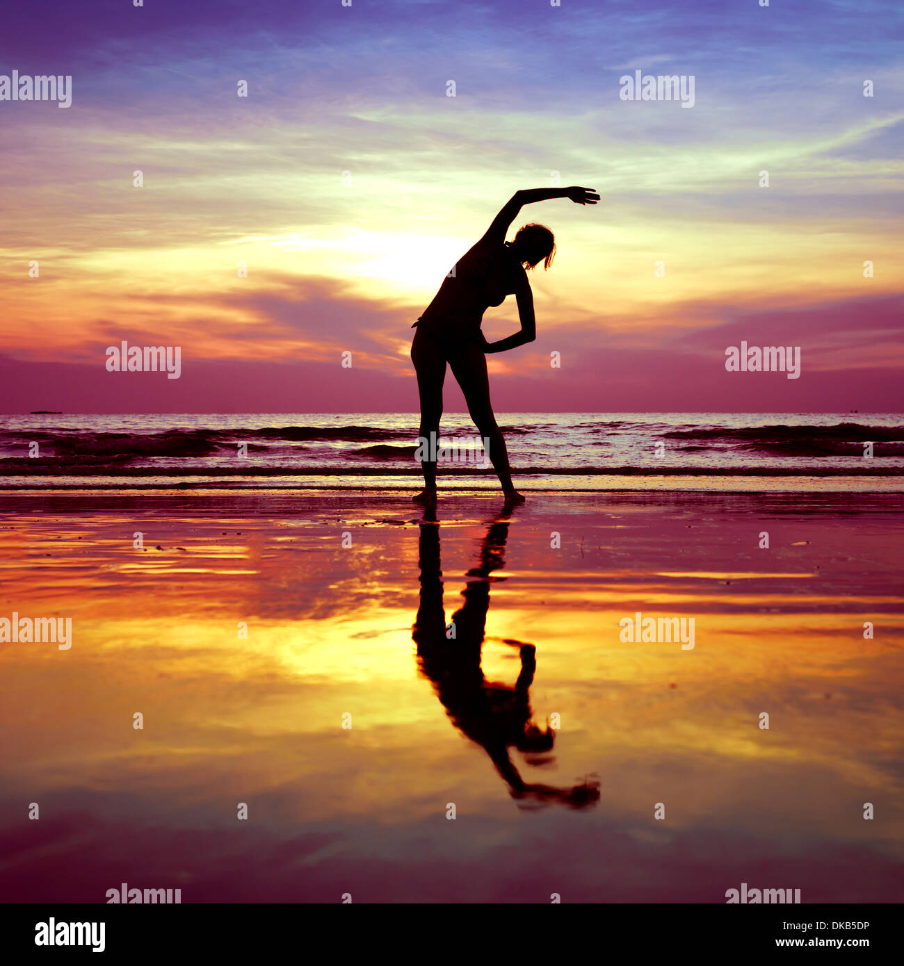 Silhouette der jungen Frau, Yoga, stretching-Übungen am Strand bei Sonnenuntergang Stockfoto