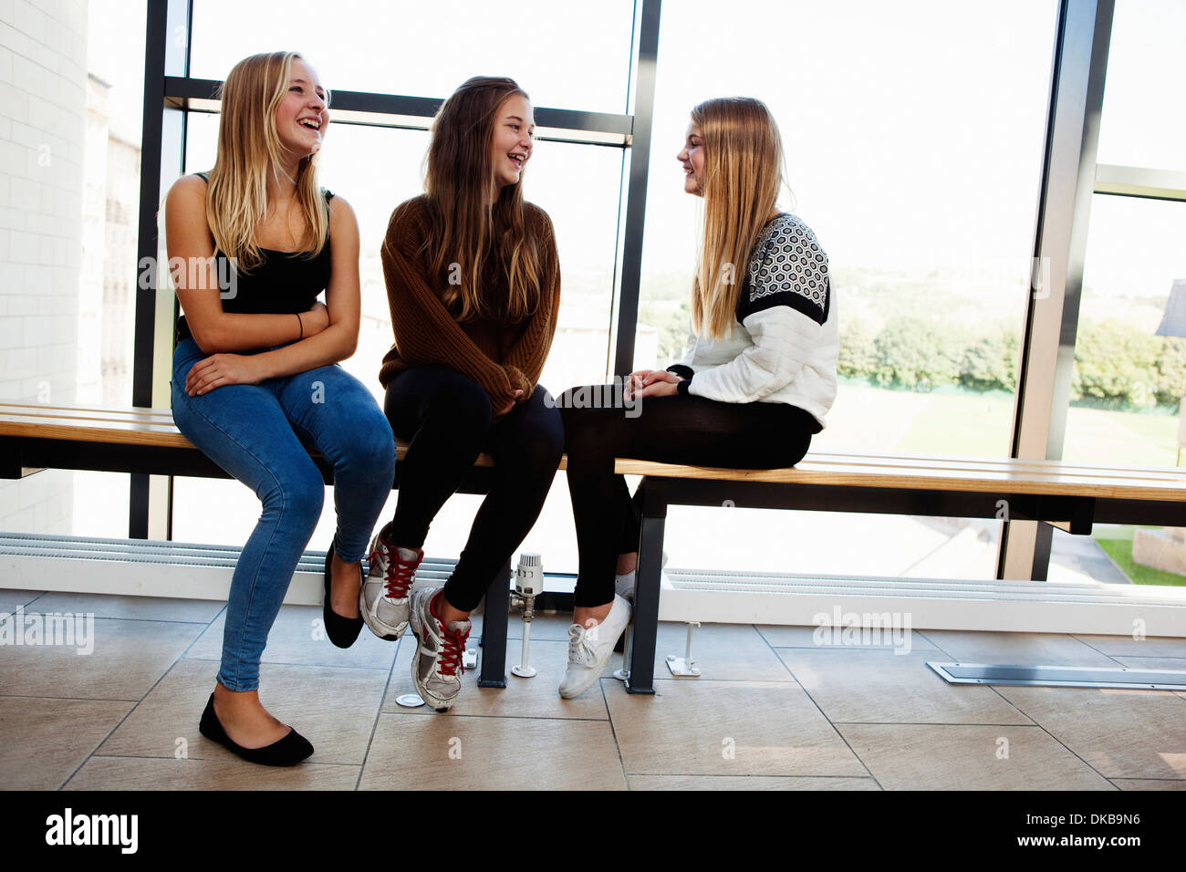 Drei Teenager Schulmädchen sitzen, plaudern im Korridor Stockfoto