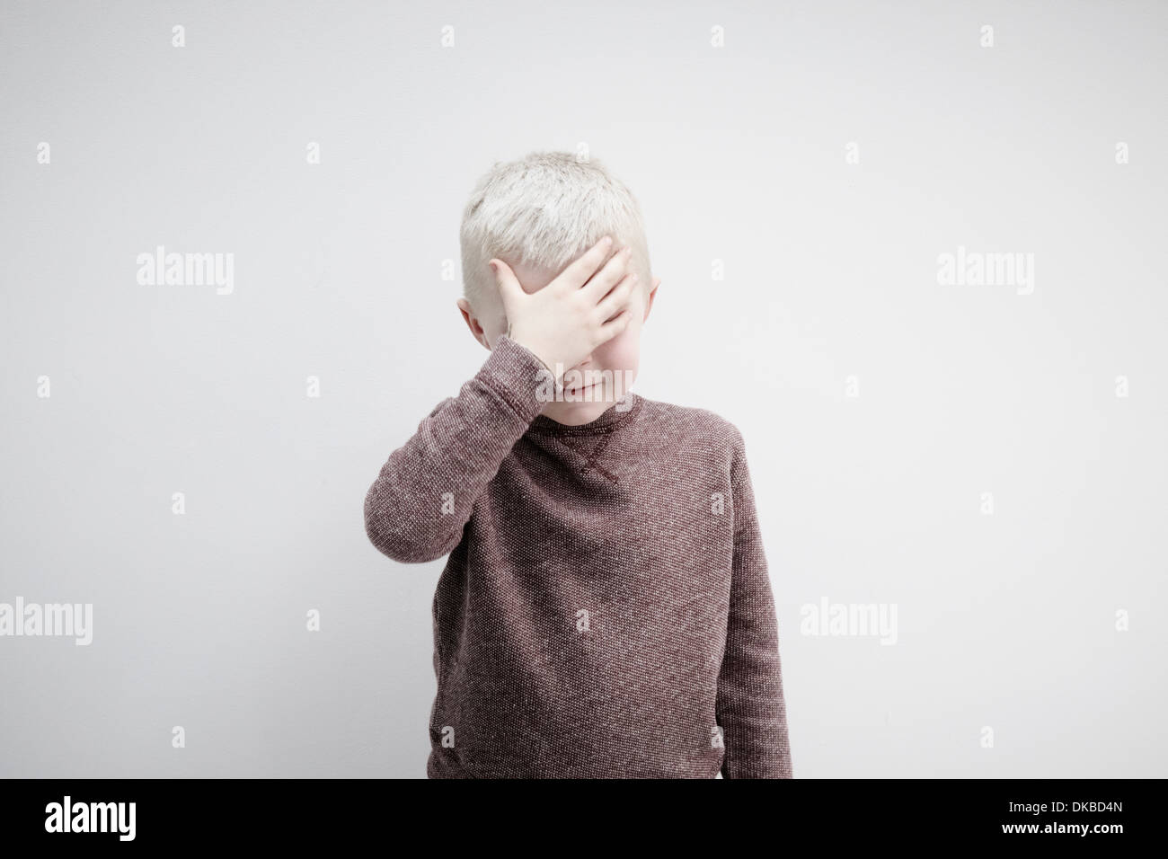 Porträt der jungen tragen braune Jumper für Gesicht mit den Händen Stockfoto