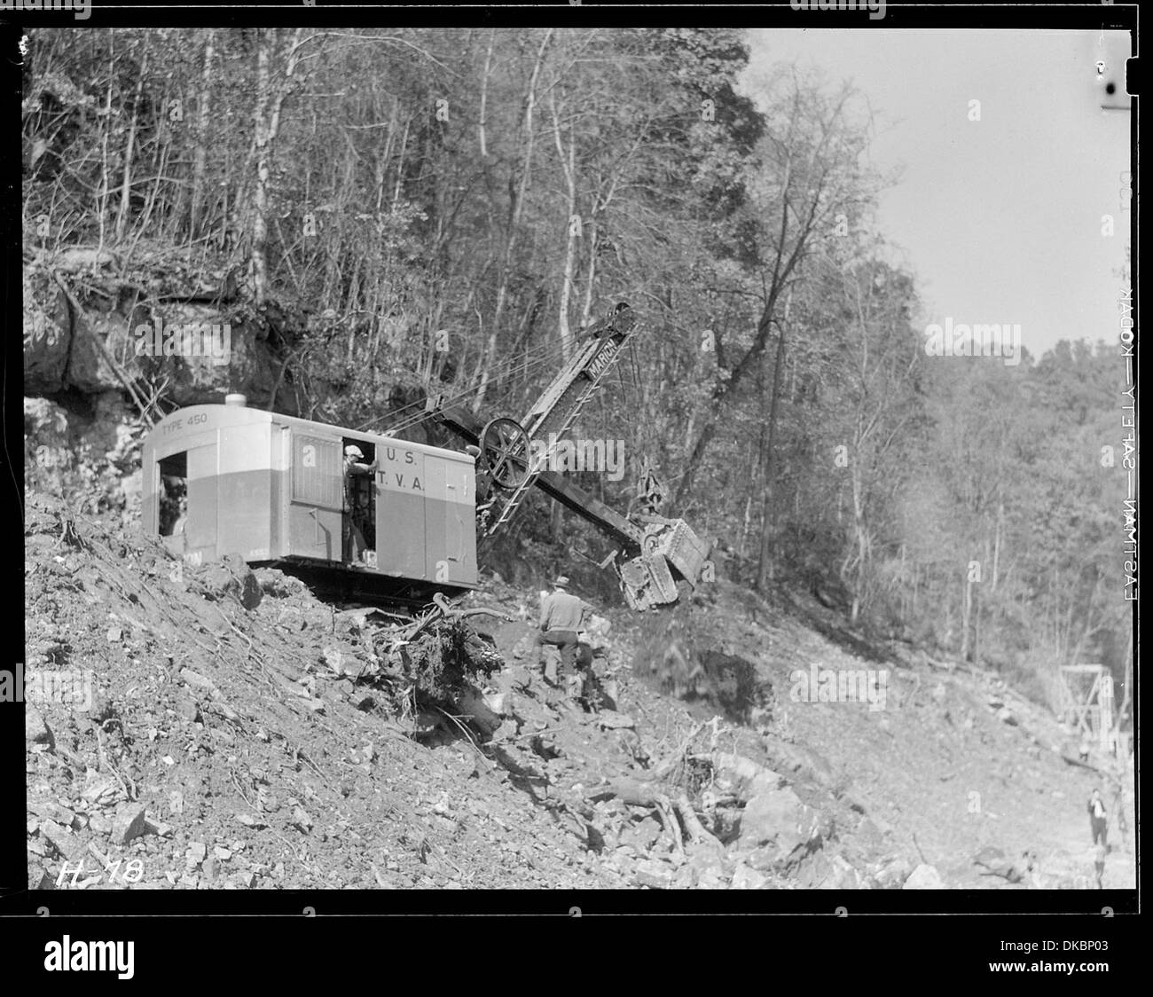 Auf einer Fahrbahn am Hang auf der Baustelle des Norris Dam läuft eine Schaufel. Die Maschine wird verwendet, um Erde zu bewegen und den Bereich für den Damm vorzubereiten, was die frühen schweren Maschinen im Bau veranschaulicht. Stockfoto