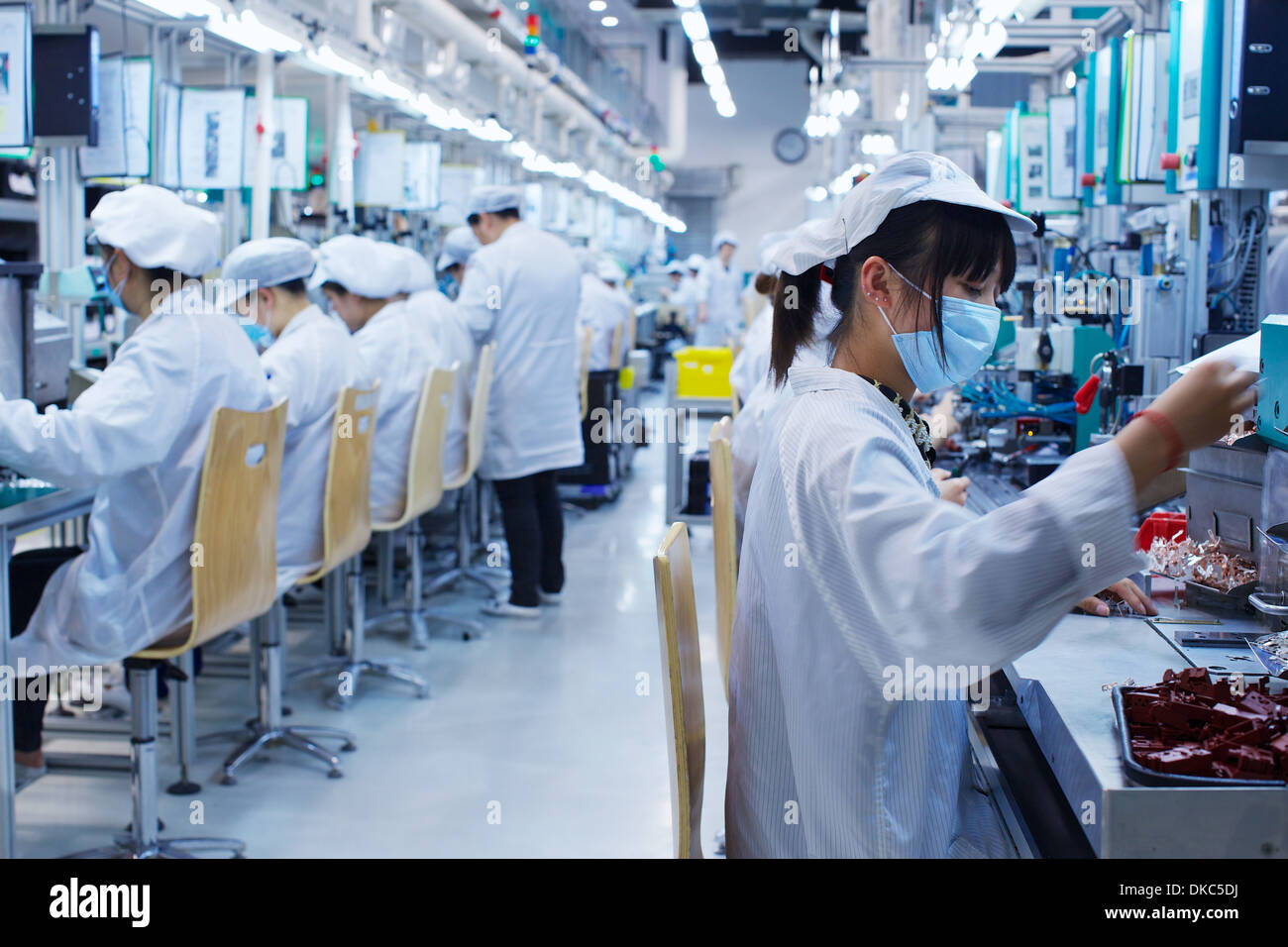 Gruppe der Arbeitnehmer bei der kleinen Teilefertigung Fabrik in China, tragen von Schutzkleidung, Hüte und Masken Stockfoto