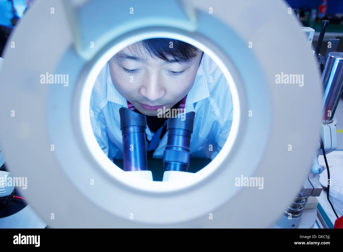 Worker bei kleinen Teilefertigung Fabrik in China durch Mikroskop Stockfoto