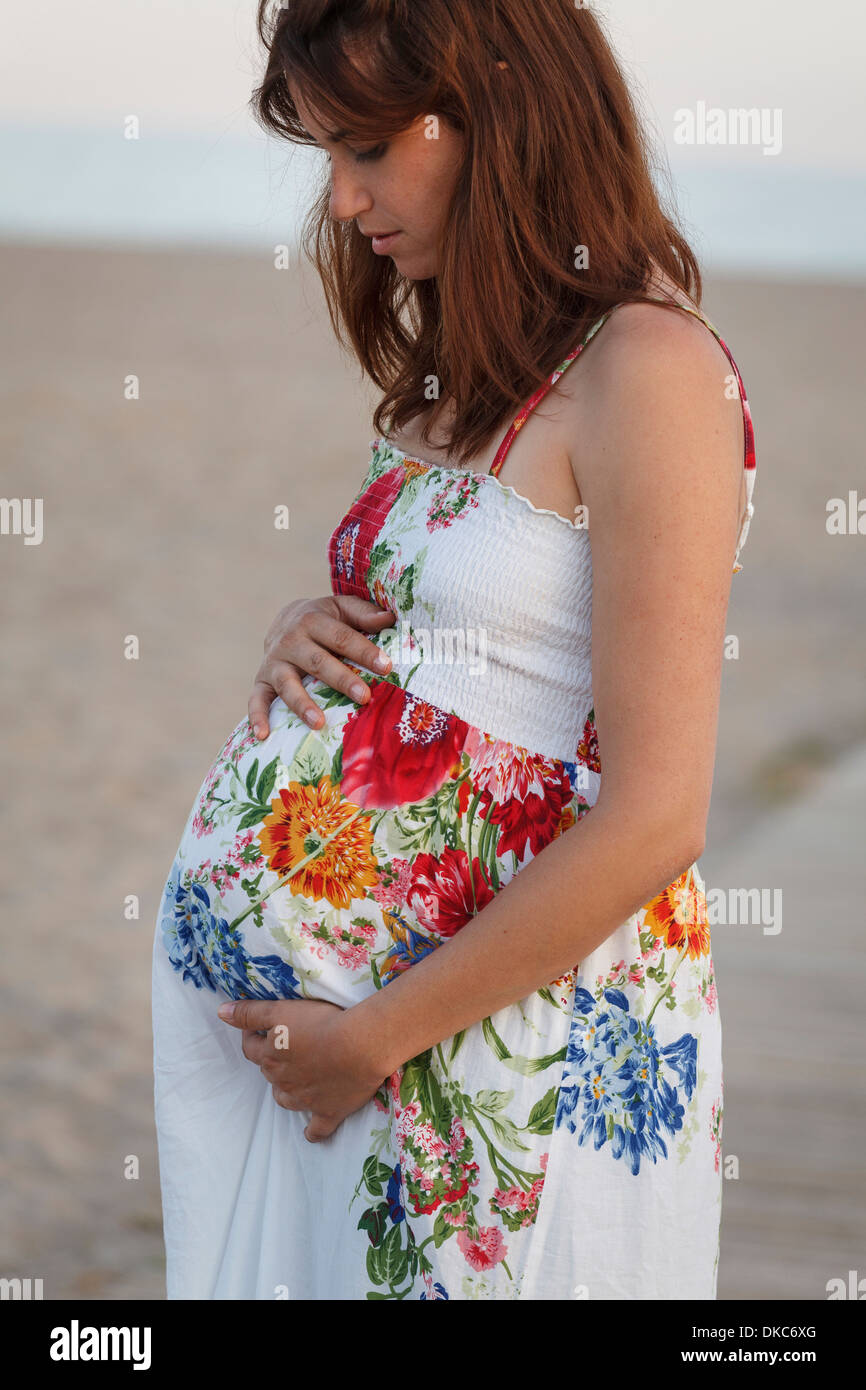 Seitenansicht der schwangeren Frau, Hände auf Bauch, auf der Suche nach unten Stockfoto