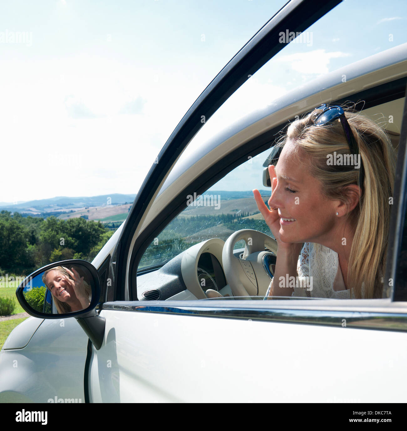 Reife Frau Anwendung machen sich im Spiegel des Autos Stockfoto