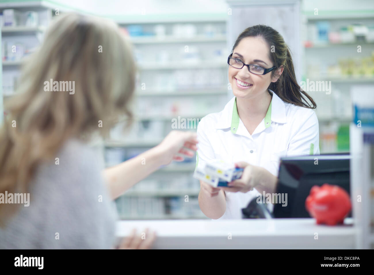Junge Frau im Gespräch mit Apotheker Stockfoto