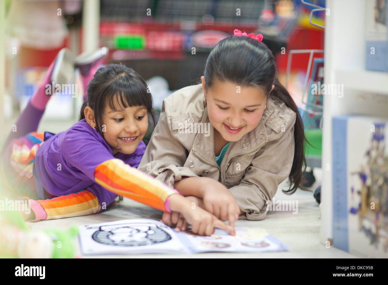 Zwei Schwestern betrachten Bilderbuch im Spielzeugladen Stockfoto