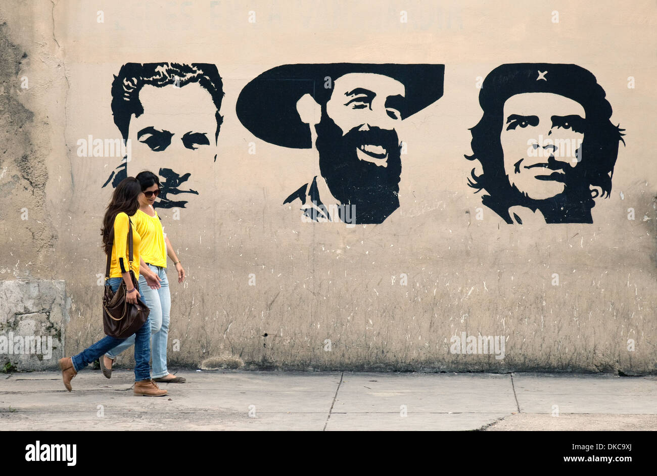 Kubanische Frauen vorbei an Graffiti der Helden der Revolution einschließlich Che Guevara und Fidel Castro; Havanna, Kuba, Caribbean Stockfoto