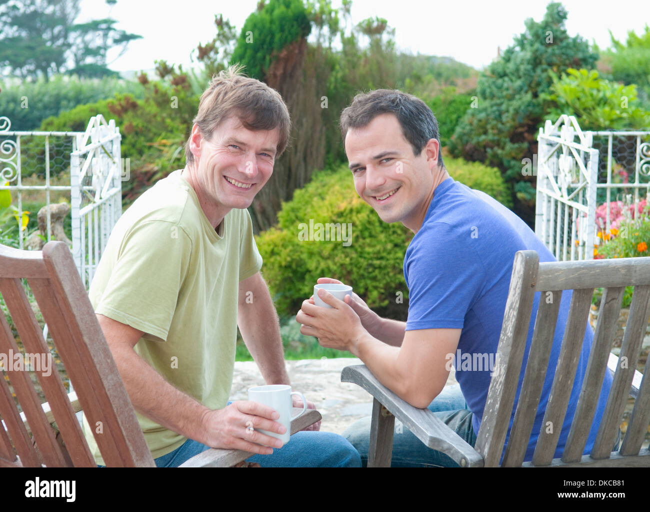 Zwei männliche Erwachsene Freunde entspannend im Garten Stockfoto