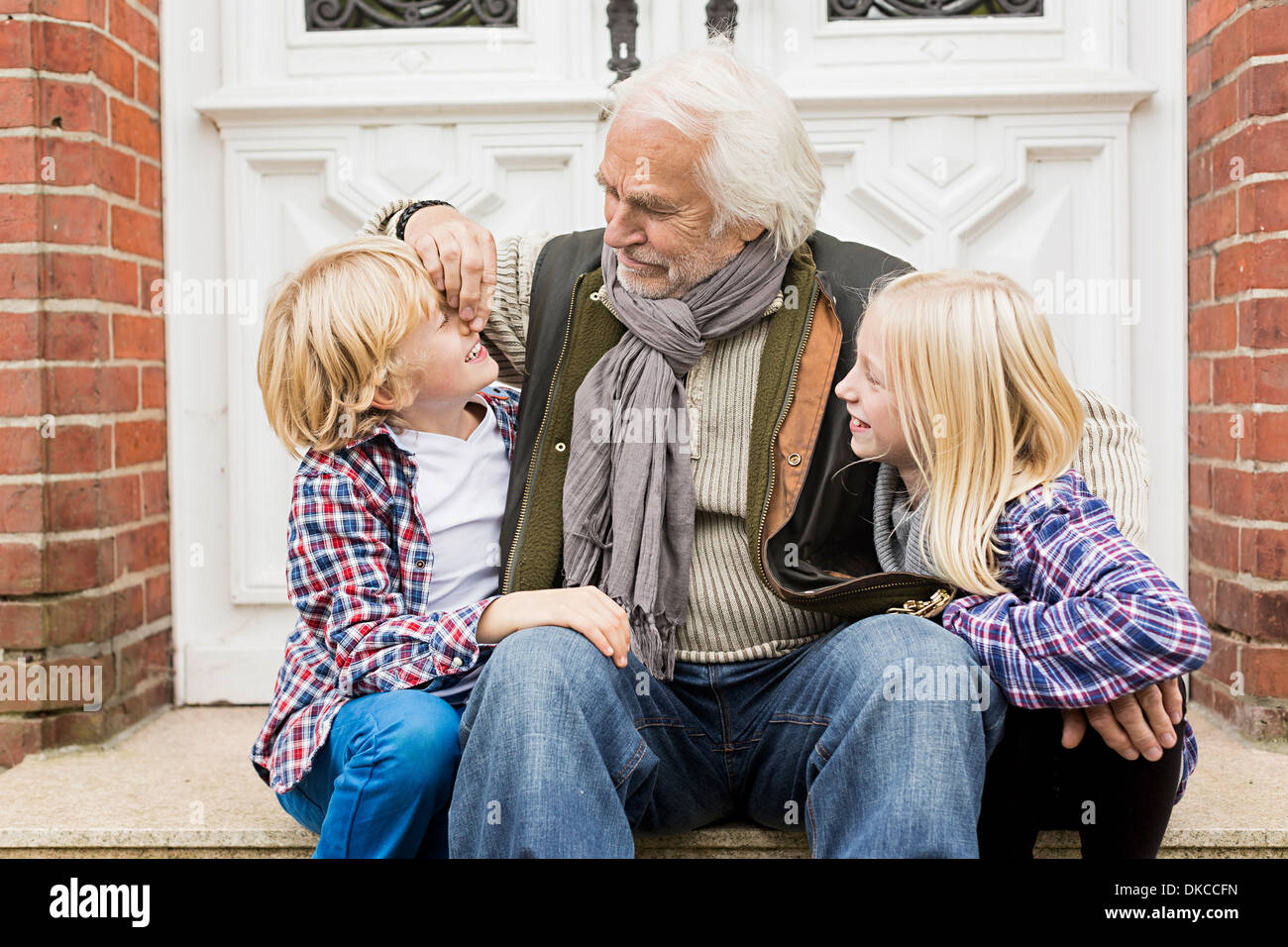 Großvater mit Enkel vor Haustüre sitzen Stockfoto