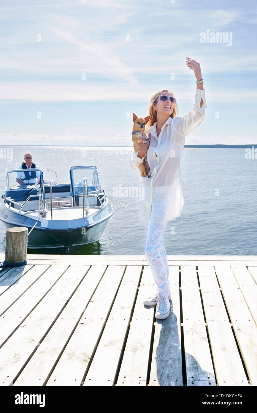 Junge Frau fotografieren sich mit Hund auf Pier, Hotels, Schweden Stockfoto