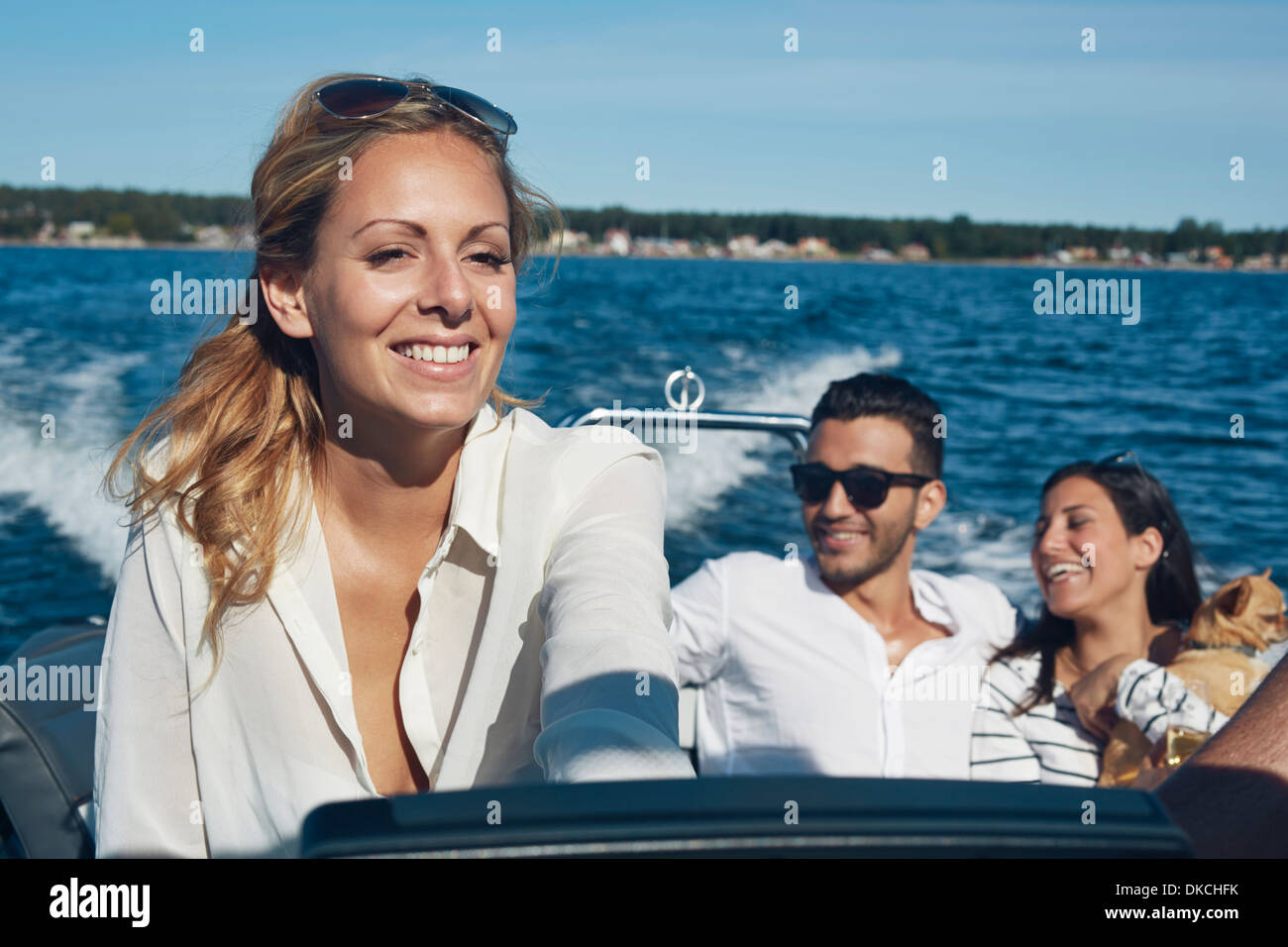 Junge Frau Lenkung Boot mit Freunden im Hintergrund, Hotels, Schweden Stockfoto