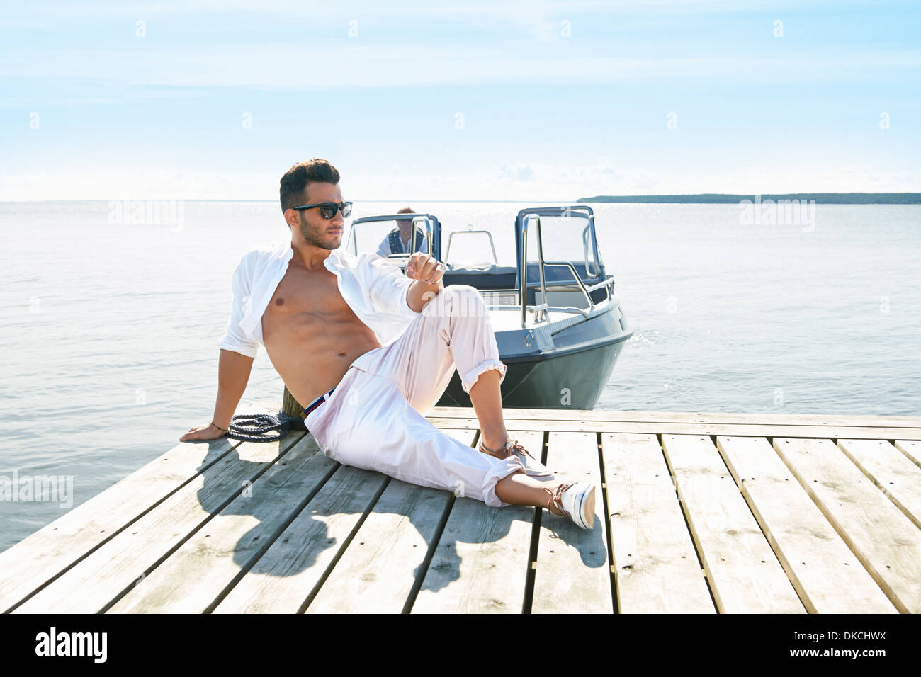 Junger Mann sitzt auf Pier, Hotels, Schweden Stockfoto