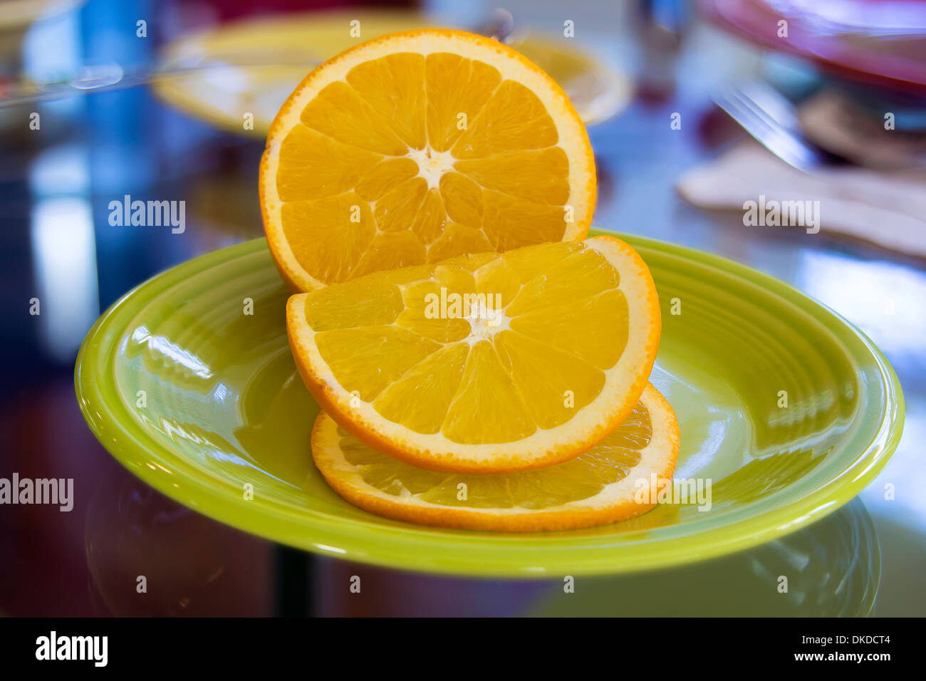 In Scheiben geschnitten Orange Früchte zum garnieren auf grüne Platte mit unscharfen Hintergrund Dinner Tischdekoration Stockfoto