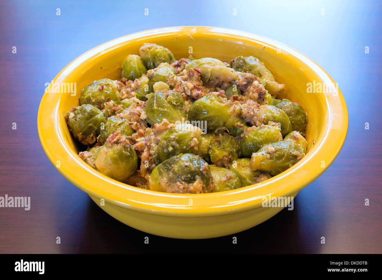 Rosenkohl mit Speck Olivenöl und Zwiebeln in gelben Schale gekocht Stockfoto
