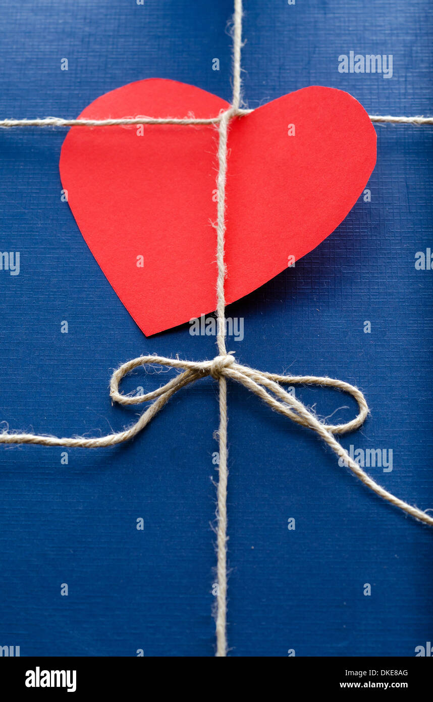 Blaues Papierpaket oder Geschenk mit roten Herz-Form-Valentine-Karte. Stockfoto