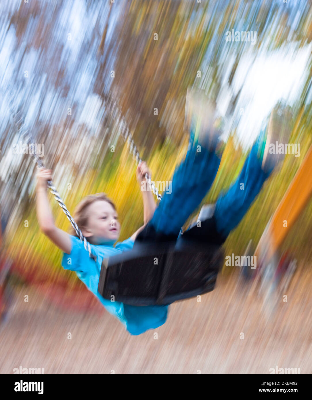 Junge auf einer Schaukel auf dem Spielplatz Stockfoto