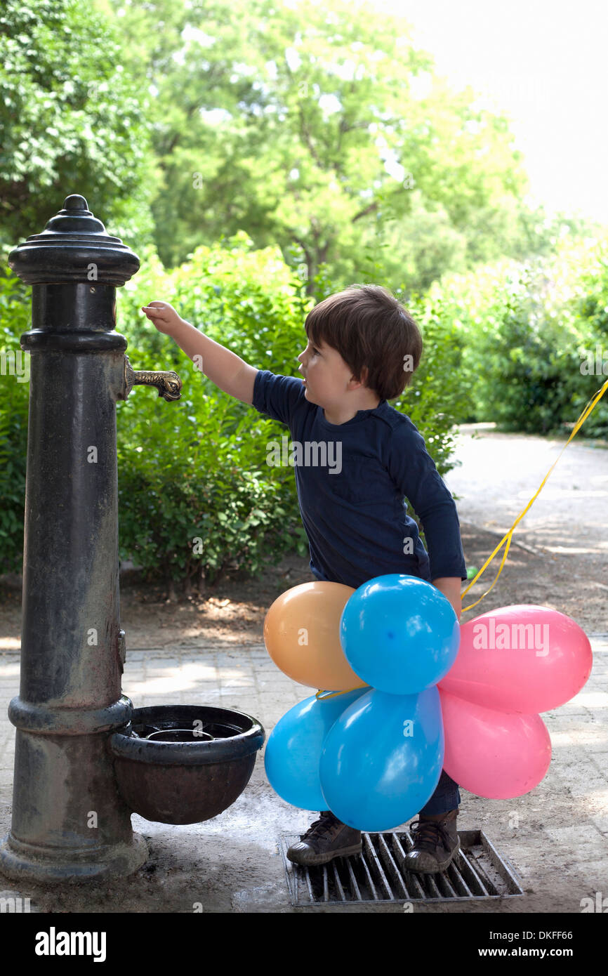 Männliche Kleinkind neugierig mit Blick auf Garten Wasserpumpe Stockfoto