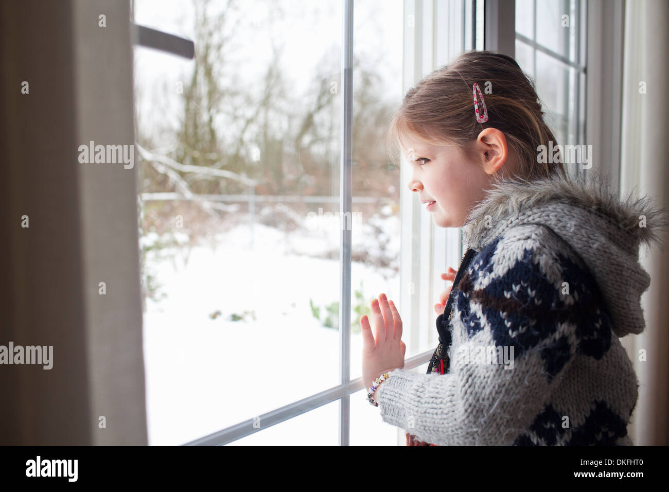 Junges Mädchen Blick aus Fenster im Garten im Schnee Stockfoto