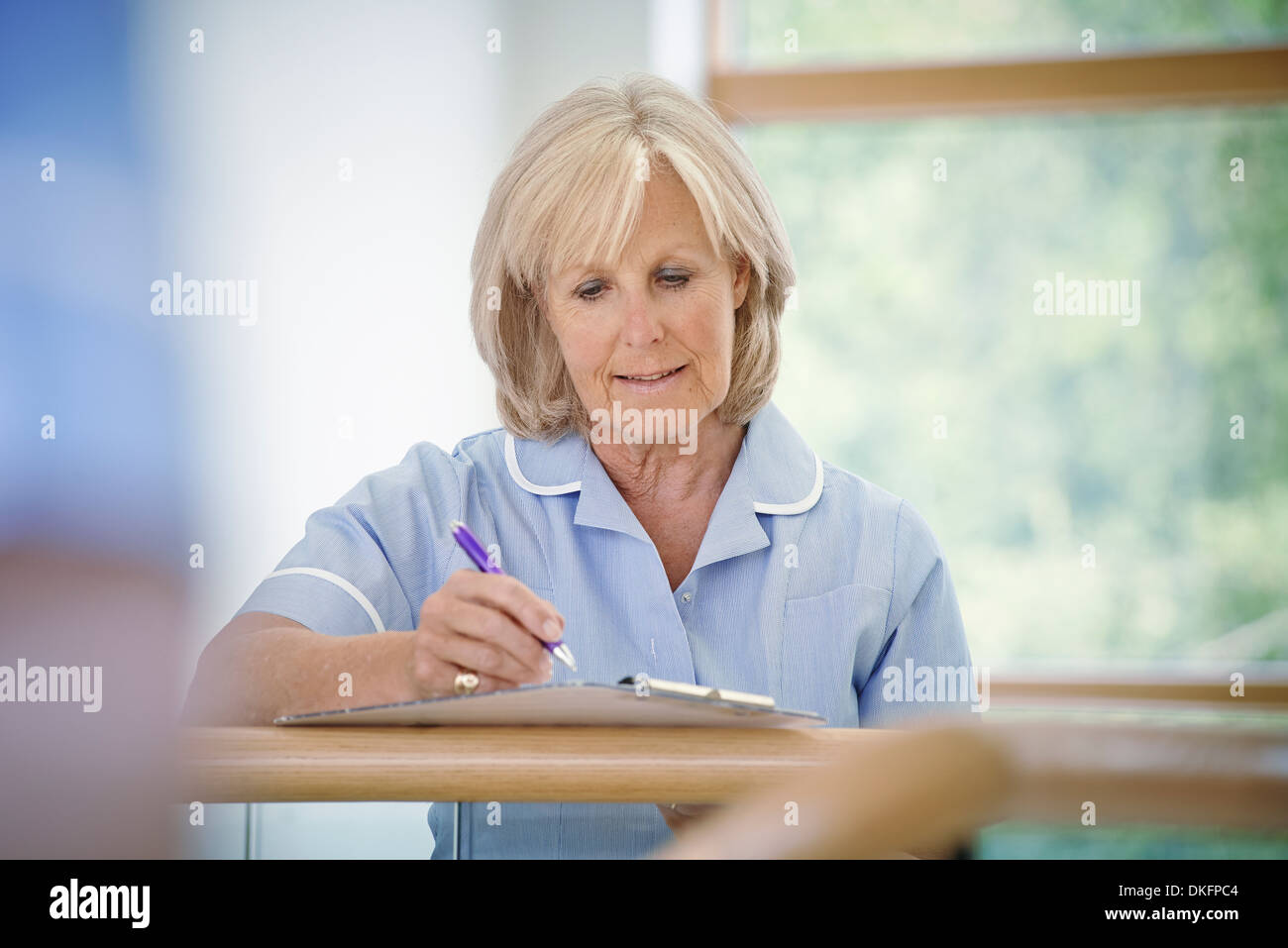 Reife Krankenschwester im Krankenhausflur mit Zwischenablage Stockfoto