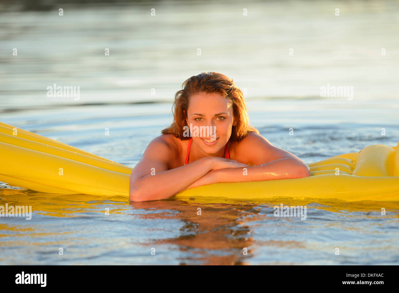 Junge Frau mit Luftmatratze im See Stockfoto
