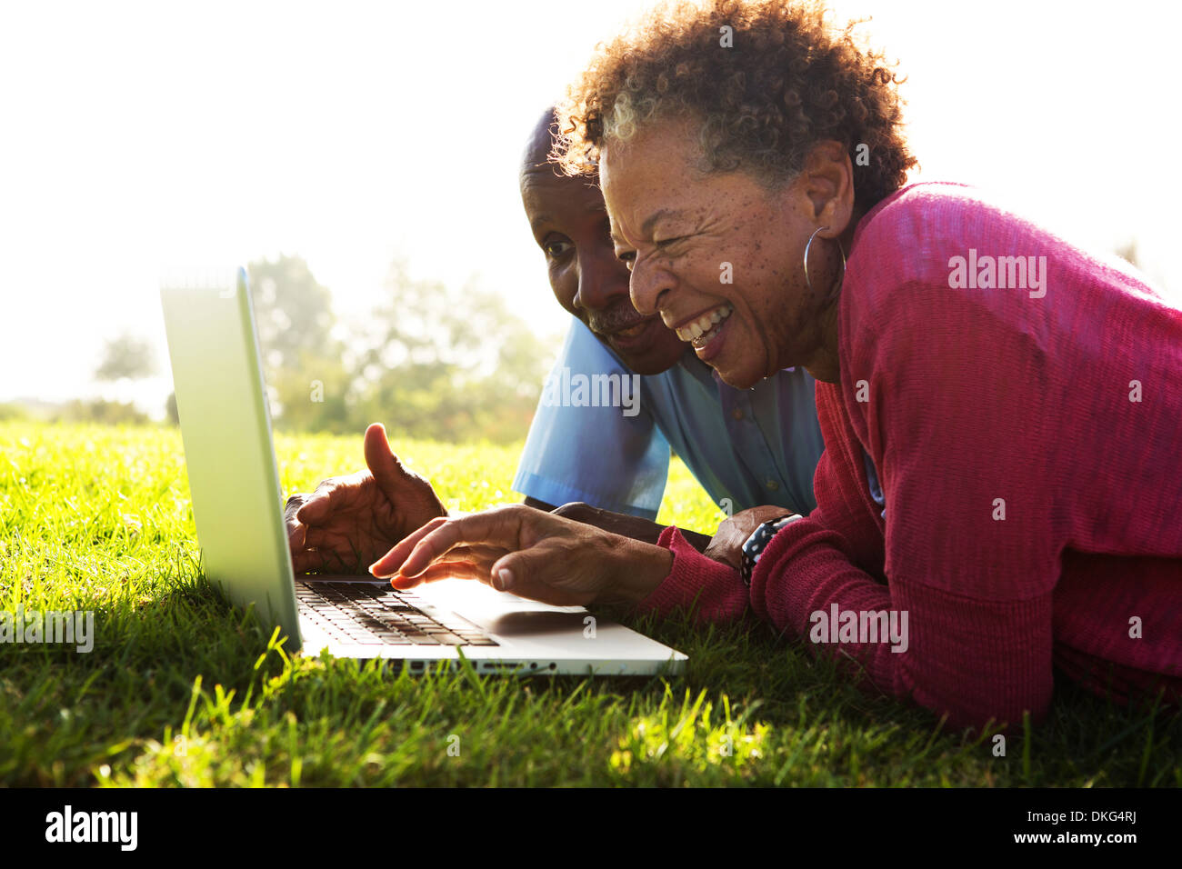 Älteres paar liegen im Park mit laptop Stockfoto