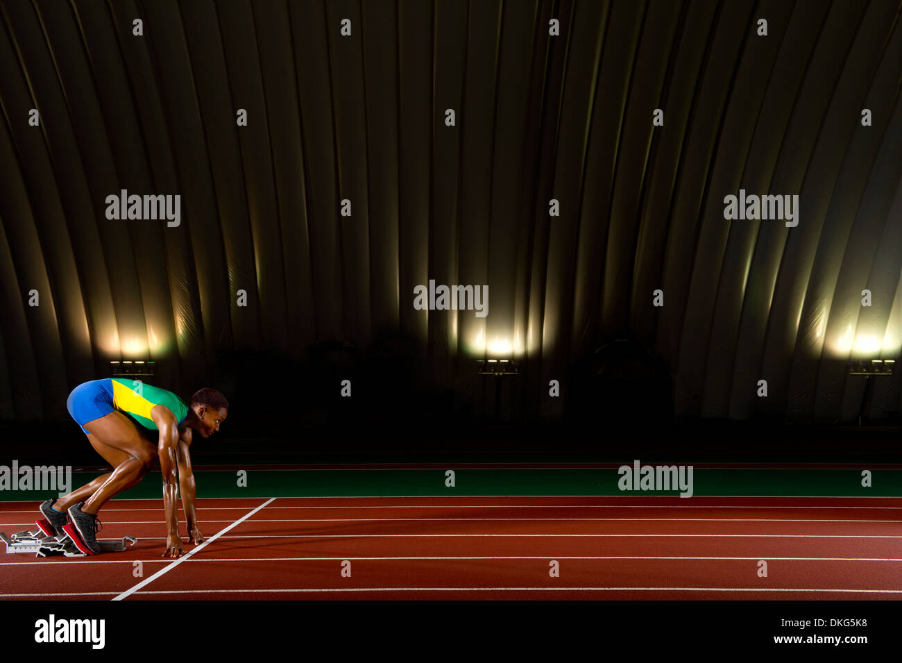 Junge Frau in Startlöchern im Stadion sprinten Stockfoto