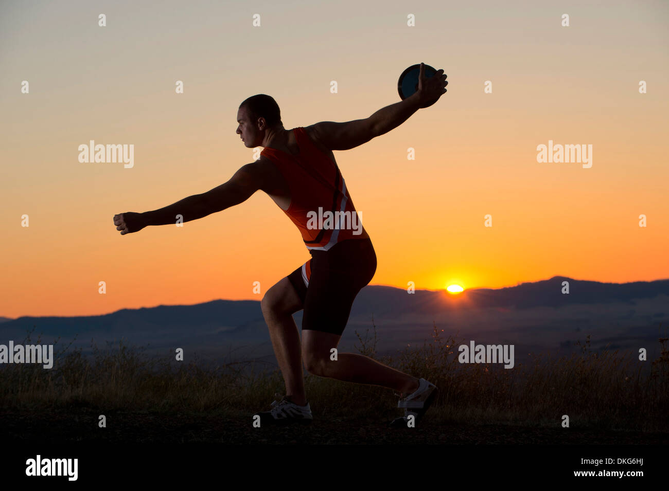 Junger Mann bei Sonnenuntergang Diskuswurf wird vorbereitet Stockfoto