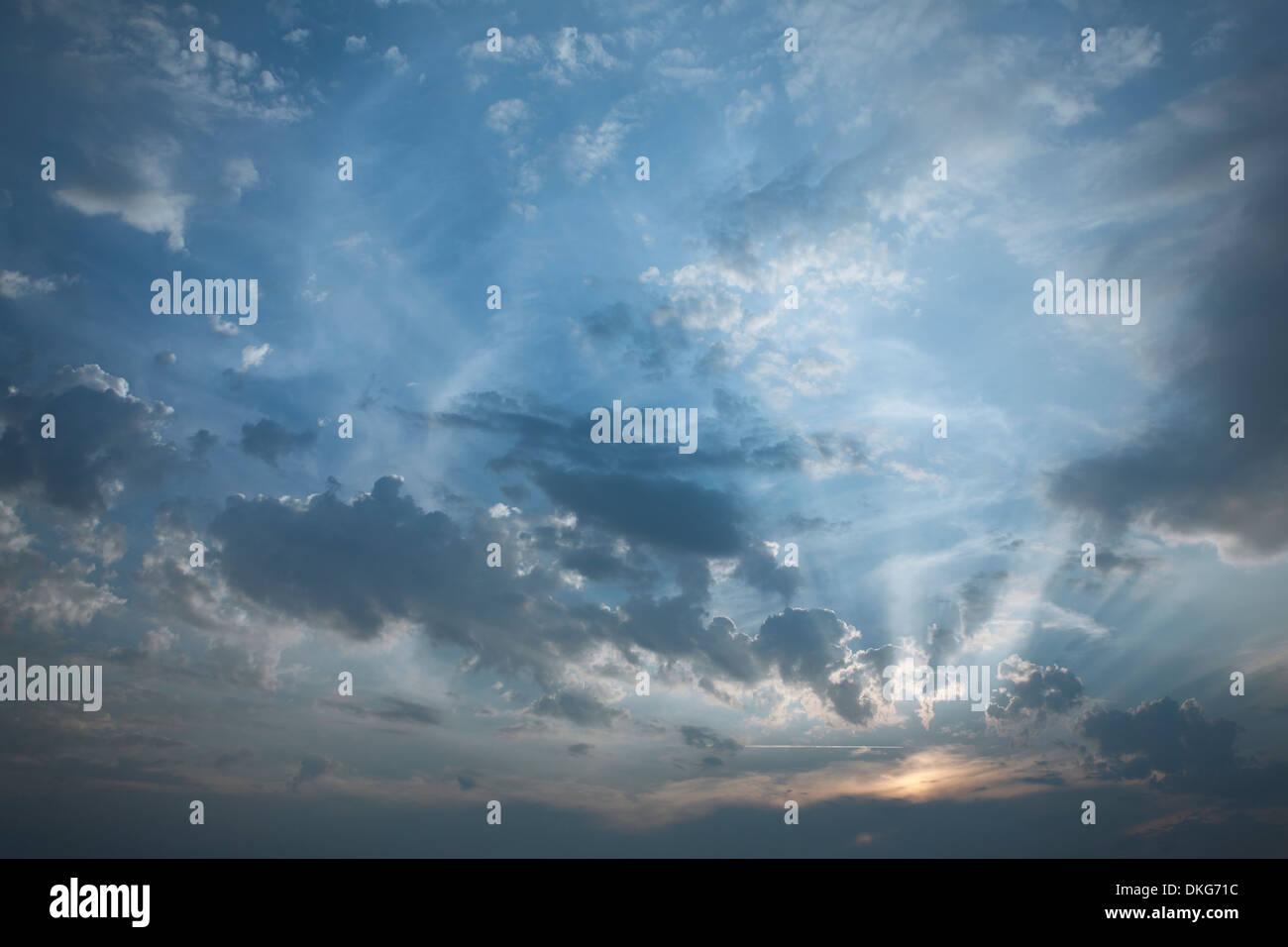 Lichtstrahlen Balg heraus aus einer milchigen untergehenden Sonne, blauer Himmel und unterschiedlichen Texturen und Schatten. Stockfoto